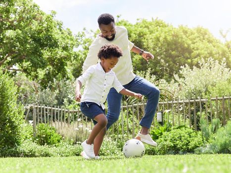 Playing like real football stars. a father and son playing soccer together outdoors.