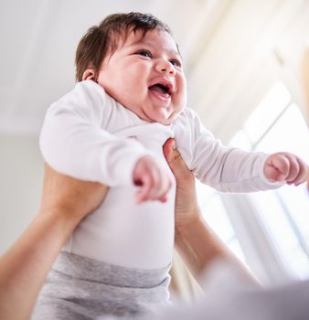 a mixed race adorable cute little baby laughing. Young mother playing with her newborn baby while laughing and enjoying bonding with her infant at home. Single mom happy on maternity leave