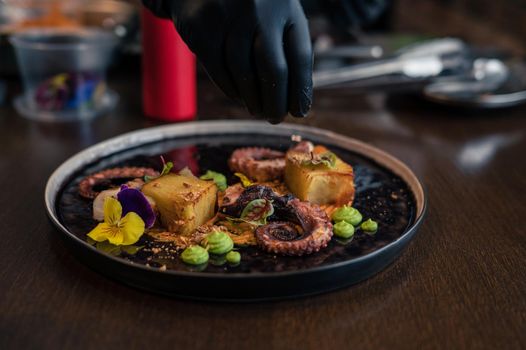 Chef preparing octopus with potatoes on pea mash