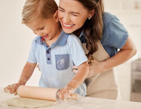 Any activity can be fun. a young mother rolling out dough with her son.