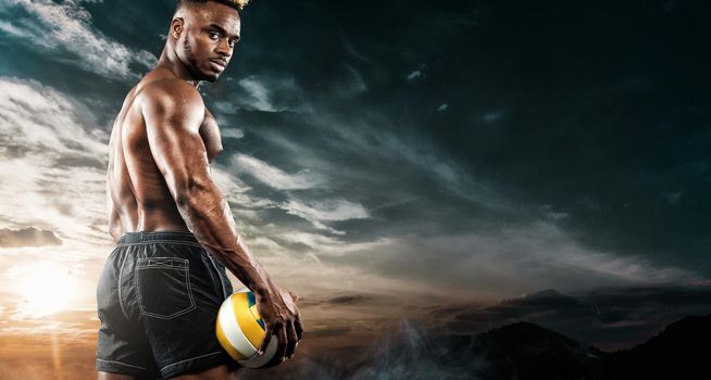 Portrait of afro-american sportsman, beach volleyball player with a ball over sky background. Fit young man in sportswear holding ball.