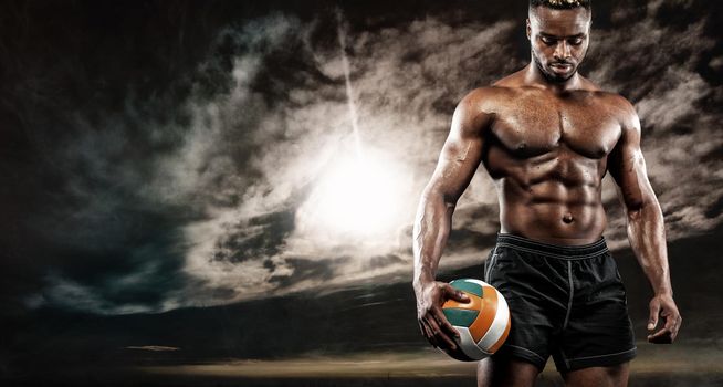 Portrait of afro-american sportsman, beach volleyball player with a ball over sunset. Fit young man in sportswear holding ball.