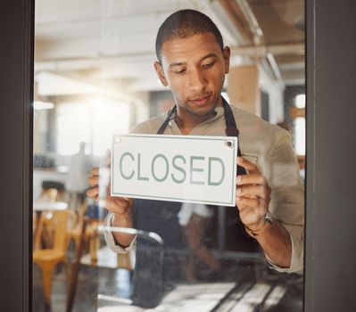 Businessman advertising that his shop is closed. Young business owner closing his restaurant. Shop owner hanging a closed sign in his store. Diner owner hanging a message in his shop entrance