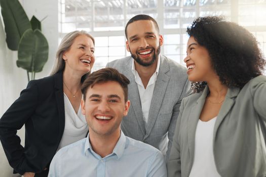 Group of four cheerful diverse and positive businesspeople taking a selfie together at work. Happy hispanic businesswoman taking a photo with her joyful colleagues