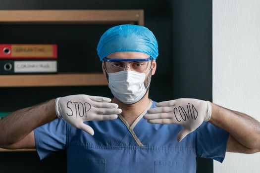 Man In Blue Medical Uniform Shows Slogan To Stop Covid