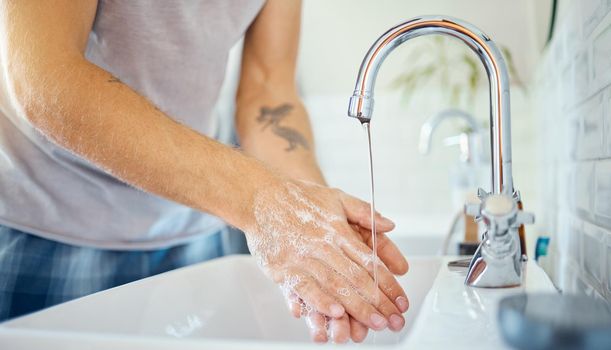 One unknown man washing his hands in a bathroom at home. Unrecognizable male using soap to kill bacteria and prevent the spread of viruses in a basin at home in his apartment