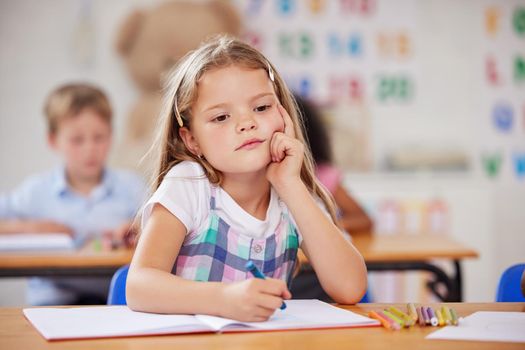 Preschool is where a child can build their imagination. a preschool student looking thoughtful while sitting in class.