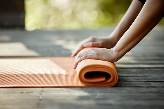 Your yoga mat is your portable workout area. Closeup shot of an unrecognizable young female athlete rolling out her yoga mat outdoors.