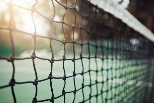 .Closeup of a tennis net on an empty court after a game during the day. Still life net with texture and detail after a competitive sports match in a sports club. Nobody playing tennis and lens flare