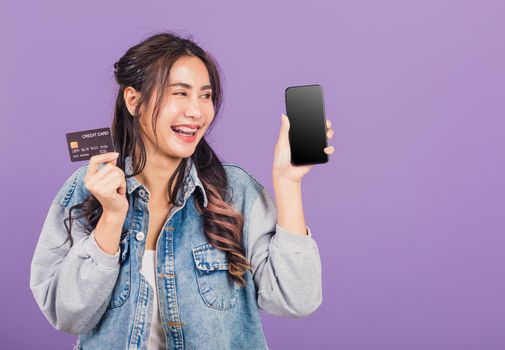 woman confident wear denim jeans shirt smiling show mobile phone blank screen and credit card bank
