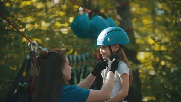Woman instructor helping a little girl putting on helmet