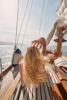 Blonde woman shaking out hair lying on boat cruising around Italy. Blonde woman relaxing on a boat touching her hair while sunbathing. Caucasian blonde woman lying on a boat sunbathing during a cruise