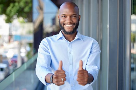 Businessman showing double thumbs in office. Smiling businessman showing double thumbs in office.
