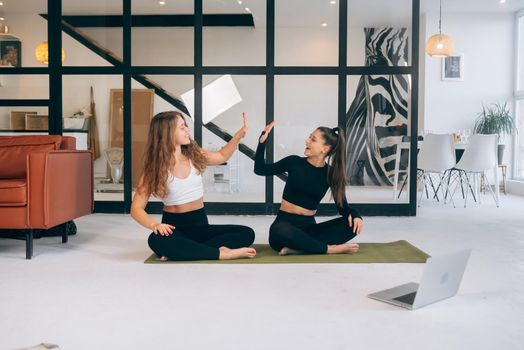Two women while sitting in the lotus position give a high five