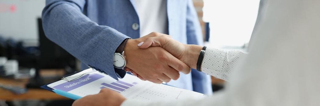 Partners shake hands over business statistics report paper