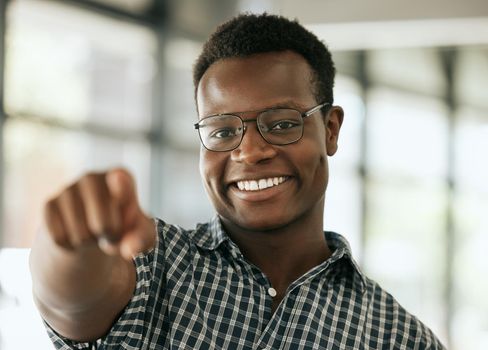 Portrait of a confident young professional african american business man with glasses pointing index finger at camera while standing in an office. HR manager choosing you