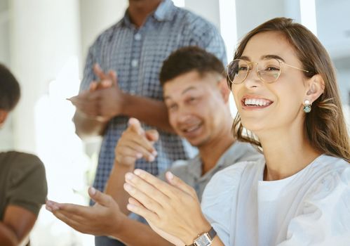 Group of joyful diverse businesspeople clapping hands in support during a meeting together at work. Happy hispanic businesswoman wearing glasses giving a coworker an applause in a workshop