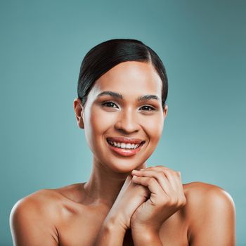 Portrait of a young beautiful mixed race woman with smooth soft skin posing and smiling against a green studio background. Attractive Hispanic female with stylish makeup posing in studio.