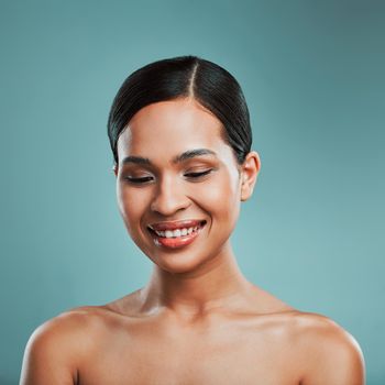 A young beautiful mixed race woman with smooth soft skin posing and smiling against a green studio background. Attractive Hispanic female with stylish makeup posing in studio.