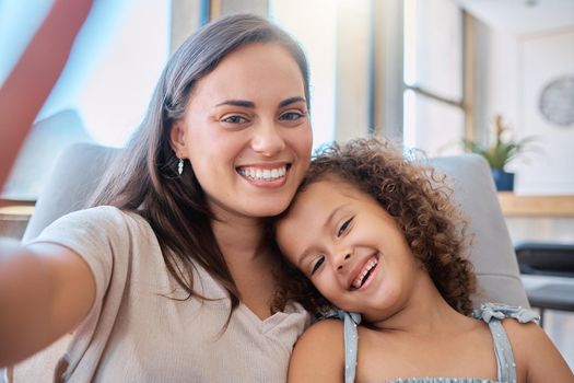 Close up of hispanic mother and little daughter smiling while taking selfie. Happy young mom having fun and taking self-portrait with adorable daughter at home