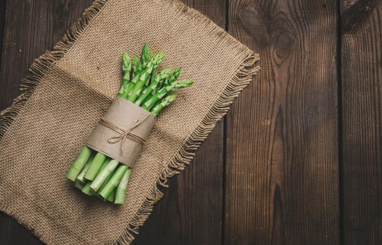 Fresh green asparagus sprouts on a wooden background. View from above