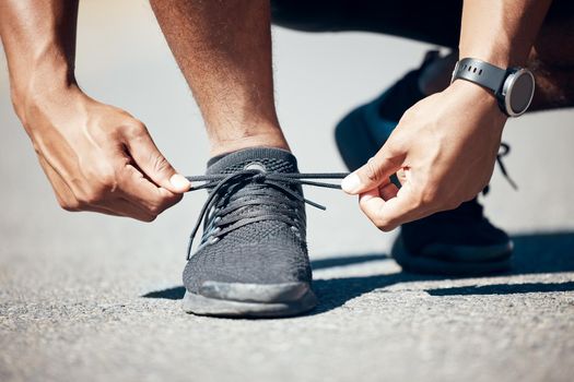 Closeup view of an unrecognisable man tying his shoelaces while exercising outdoors. Unknown male tying his laces before a run outside