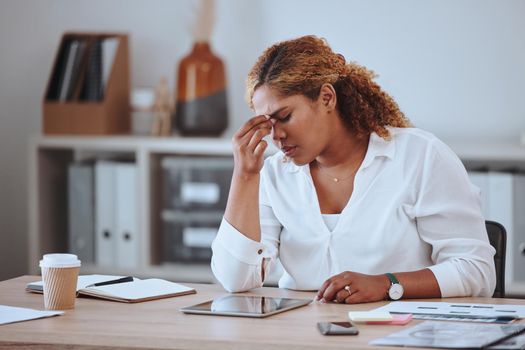 Businesswoman looking stressed with a headache. Upset businesswoman suffering a migraine. Entrepreneur frustrated with her failure. Depressed businesswoman sitting at her desk with a headache