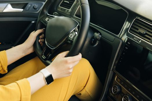 Woman hands holding a steering wheel confidently. Female hands with a clock on the steering wheel of a car while driving