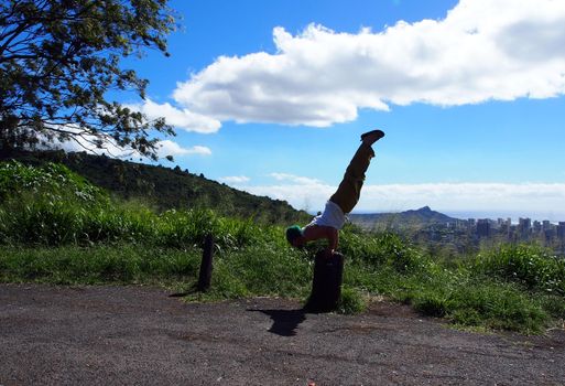 Man does Mayurasana or Peacock Pose on tree stump in the mountains of Oahu