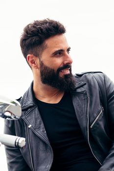 man in leather jacket leaning on his motorcycle