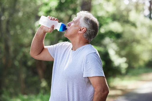 Ensure you are getting adequate hydration during your workouts. a mature man drinking water while exercising outdoors.