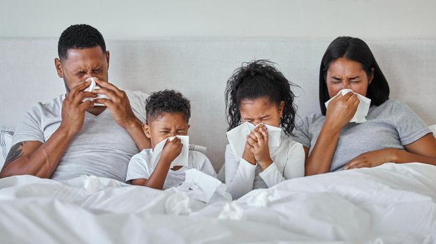 Flu season. a family blowing their noses while sick at home.