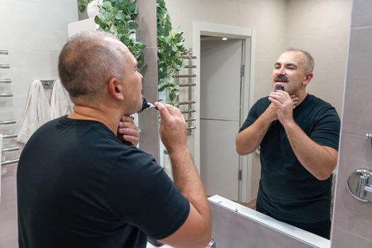 Man shaving with razor using foam in bathroom in the morning