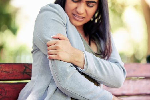 Where did this sharp pain suddenly come from. Closeup shot of a young businesswoman experiencing arm pain outdoors.