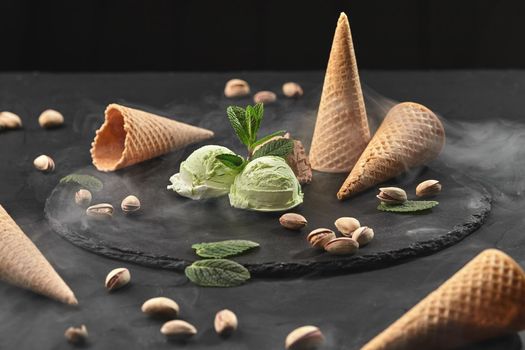 Gourmet chocolate and pistachio ice cream served on a stone slate over a black background.
