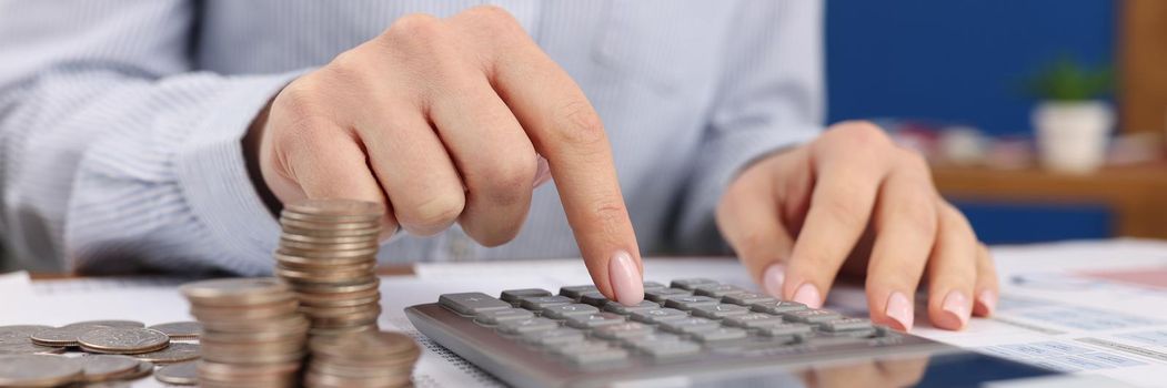 Female count on silver calculator, cash coins on office desk