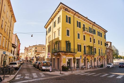 Verona, Italy - October 12, 2021: Intersection with pedestrian crossings, cars and a yellow house in Verona, Italy