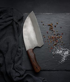 Large kitchen knife on a black graphite board and spices
