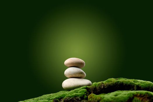 Stack of round stones on green moss, green background. Podium to showcase products