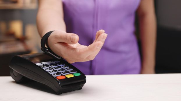Contactless payment with your smart watch. Wireless payment concept. Close-up, woman using smartwatch cashless wallet NFC technology to pay order on bank terminal. Mobile payment