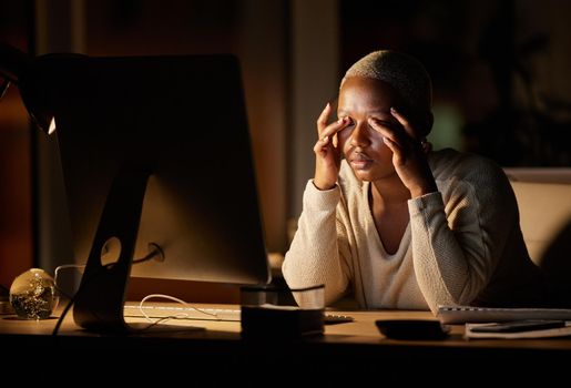 My eyes just want to stay shut. a young businesswoman looking stressed out while working on a computer in an office at night.