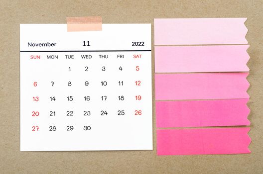 The November 2022 calendar with blank adhesive note paper on brown background.