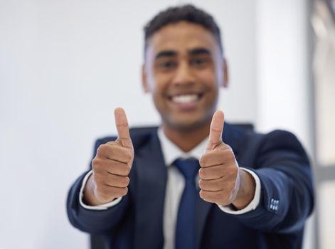 Im wishing you tons of success. Closeup shot of a young businessman showing thumbs up in an office.