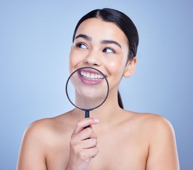 A beautiful mixed race woman posing with a magnifying glass. Young hispanic obsessed with oral hygiene against a grey copyspace background