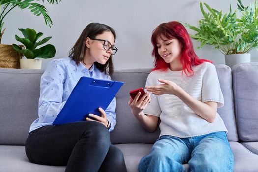 Psychologist counseling teenage female, individual therapy in doctors office.