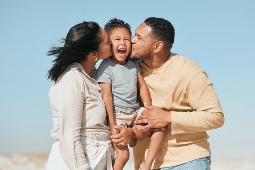 Happy mixed race family standing on the beach. Loving parents kissing adorable little son on the cheeks showing love and affection while enjoying beach vacation