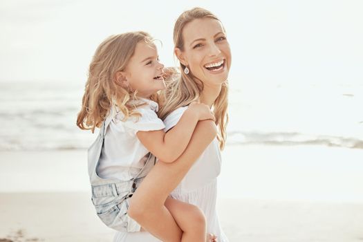 Cheerful mother and daughter having fun at beach. Young mother giving her daughter piggyback ride at beach. Precious mother and daughter relationship