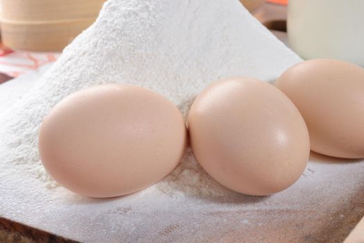 three chicken eggs on a cutting board with flour