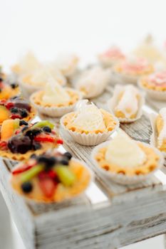 Variety of tasty appetizing sweet desserts with cream, berries and pastry, bakery and cakes on the grand wedding table at celebrate