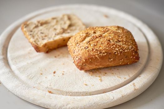 Sliced seeded wholemeal bread. Fresh brown homemade slices or roll on a wooden cutting board served as a wholesome lunch, breakfast snack meal. Healthy and organic whole wheat or grain loaf